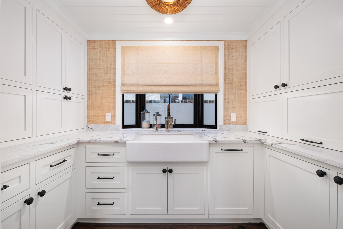 White painted scullery with farmhouse sink and grasscloth walls