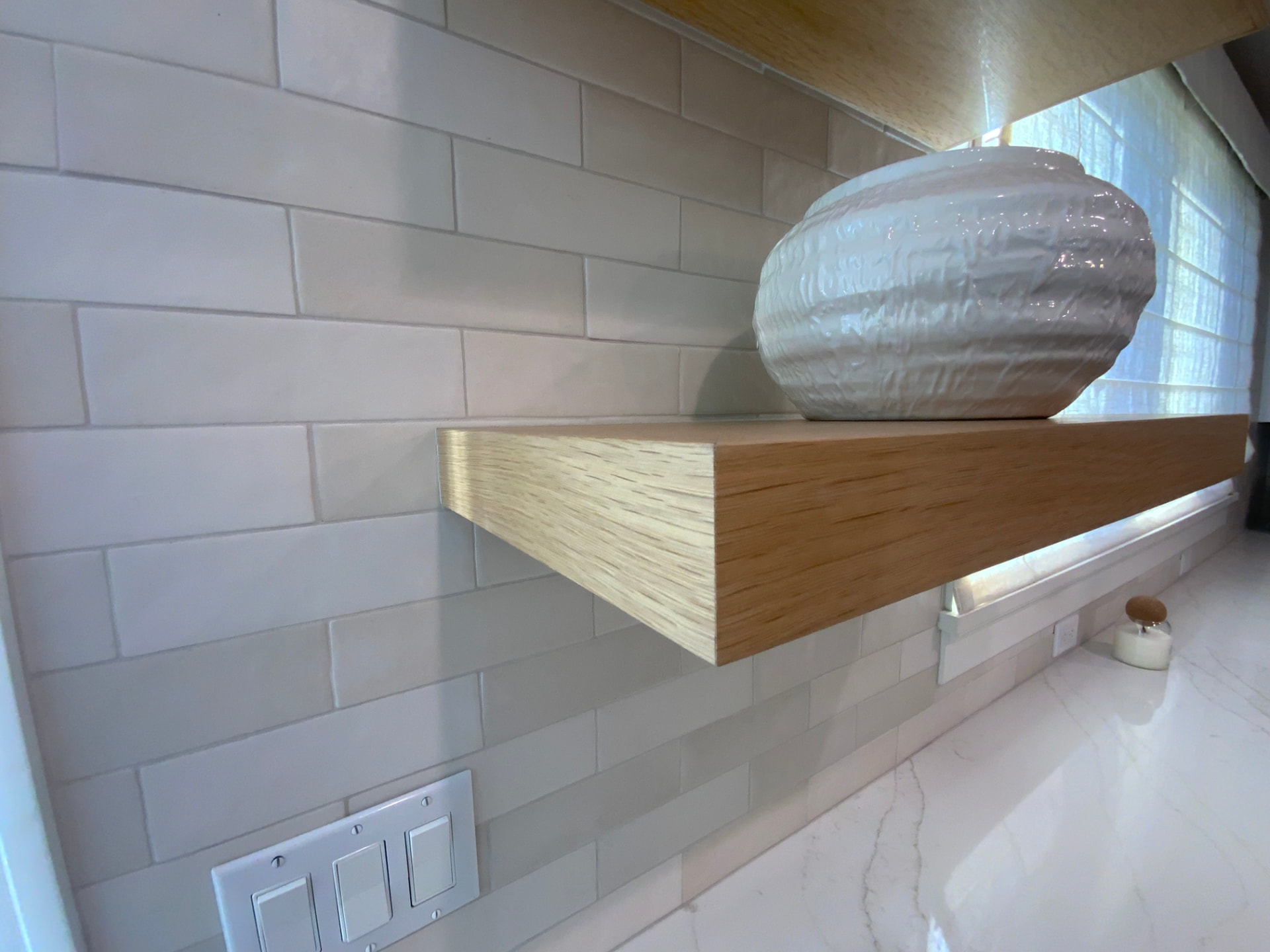 Edge-banded architectural veneer plywood floating shelf installed in a kitchen by Riggins Wood Products