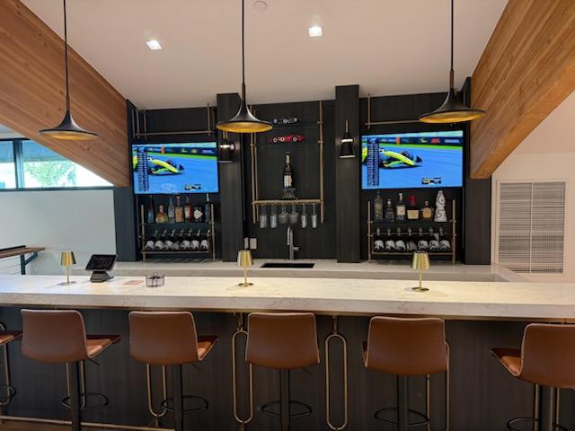Commercial bar with dark millwork, brass shelving, and marble countertops