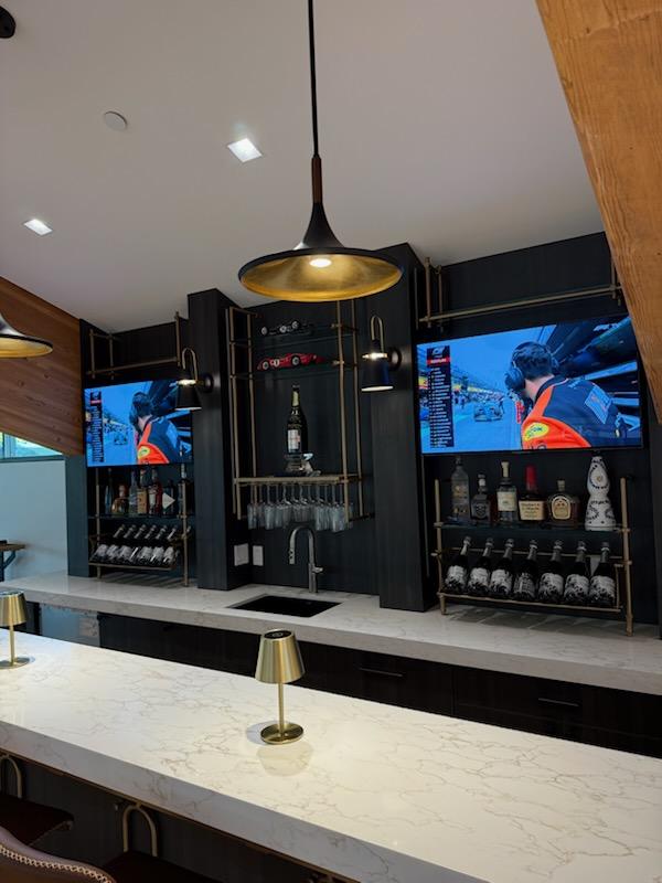Marble bar top with brass pendant lighting and dark paneled millwork